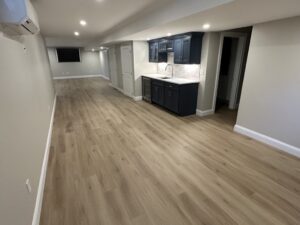 Spacious modern basement with wood flooring and cabinets.