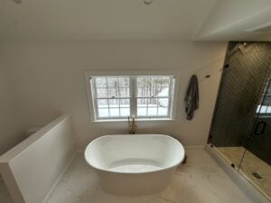 Modern bathroom with freestanding bathtub and window view.